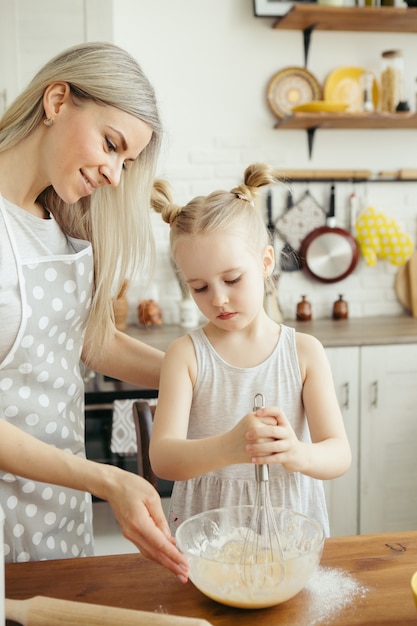 Cute little girl helps mom bake cookies in the kitchen. Happy family. Toning.