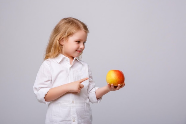 Cute little girl holding an apple on a white background