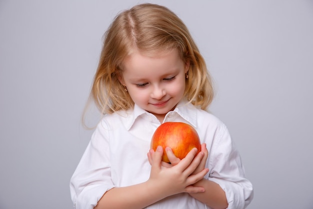 Cute little girl holding an apple on a white background