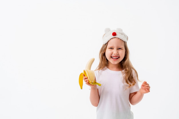 Cute little girl holding banana in her hand isolated