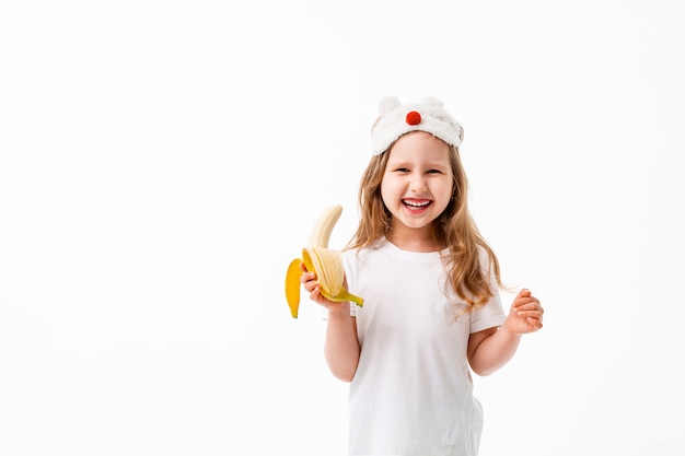 Cute little girl holding banana in her hand isolated