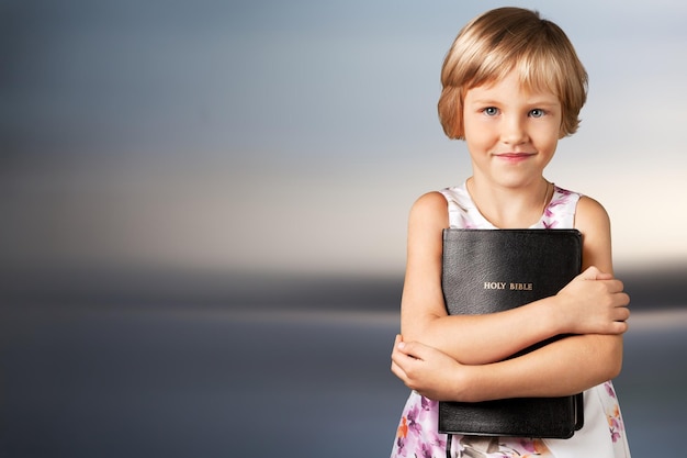 Cute little girl holding Bible on  background