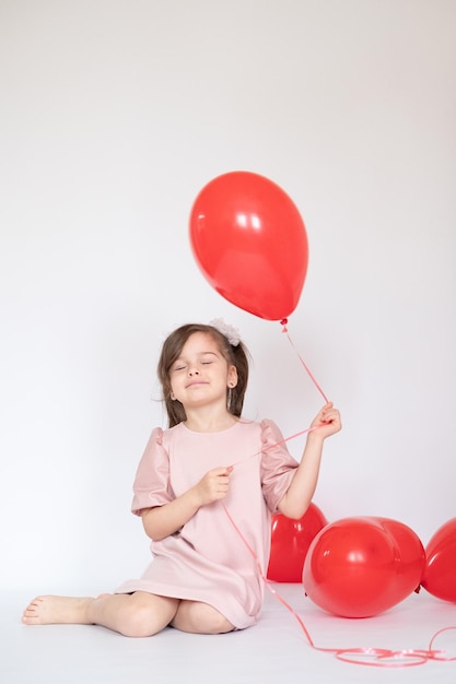 Cute little girl holding a bunch of red heartshaped balloons