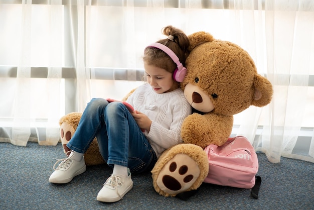 Cute little girl holding tablet computer in her hands She is in headphones Children use technology