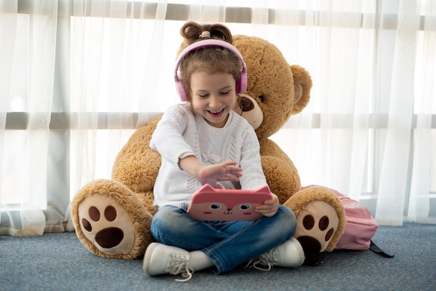 Cute little girl holding tablet computer in her hands She is in headphones Children use technology