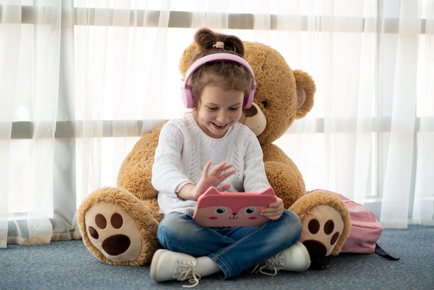 Cute little girl holding tablet computer in her hands She is in headphones Children use technology