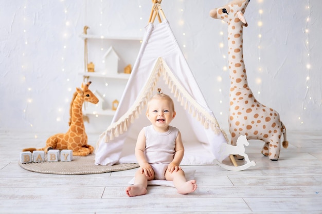 A cute little girl is sitting in a bright cozy children's playroom Textiles for children for the nursery A happy child