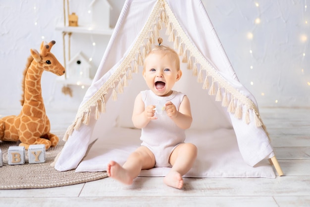 A cute little girl is sitting in a bright cozy children's playroom Textiles for children for the nursery A happy child