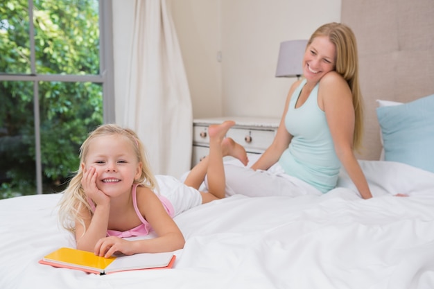 Cute little girl and mother on bed