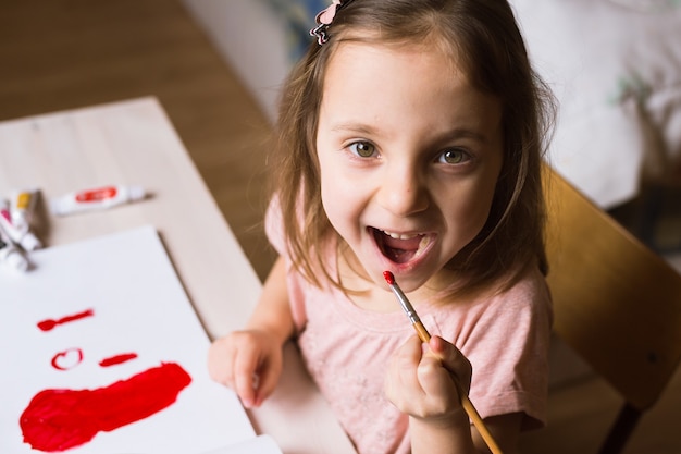 Cute little girl painting picture on home interior