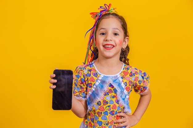 Cute little girl in party outfit holding smartphone with blank screen for text