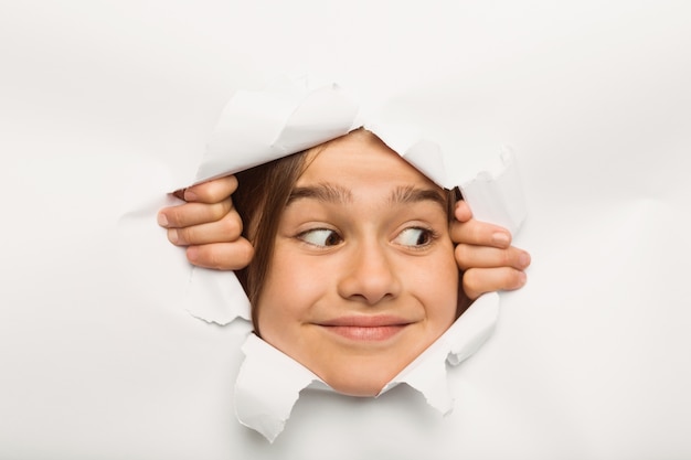 Cute little girl peeking through paper