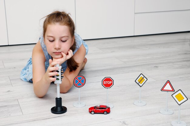 cute little girl playing at home on the floor with a typewriter road signs and traffic lights