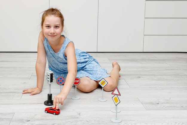 cute little girl playing at home on the floor with a typewriter road signs and traffic lights