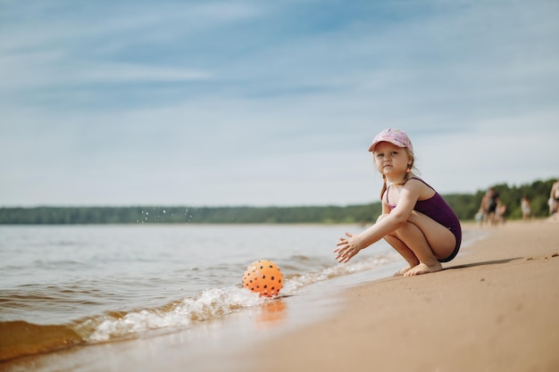 Cute little girl playing with rubber ball in sea