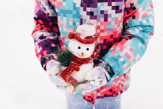 Cute little girl playing with snowman toy in winter park merry christmas concept outdoor winter