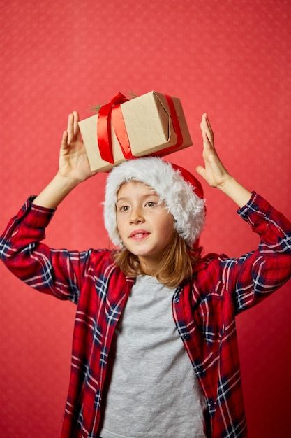 Cute little girl in santa hat with a Christmas gift on her head