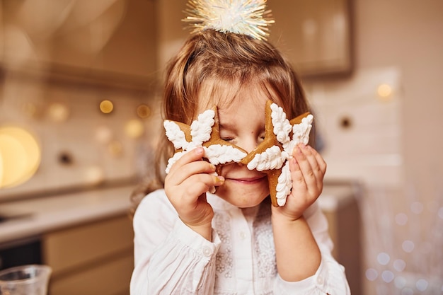 Cute little girl sitting and have fun on the kitchen with food.