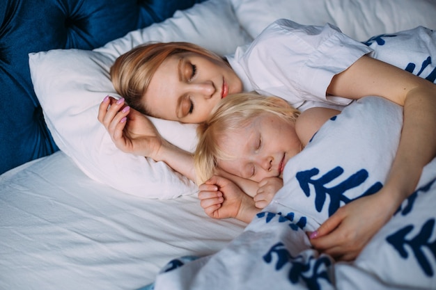 Cute little girl sleeping with mother in bed. Interior. Concept care