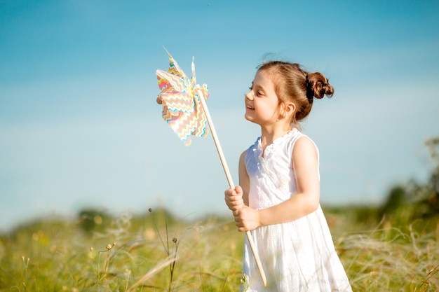 Cute little girl smiling summer in the field holding a windmill