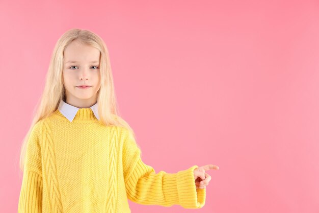 Cute little girl in sweater on pink background