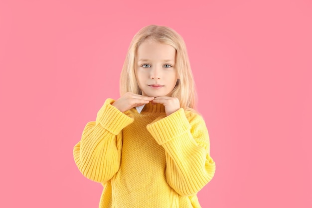 Cute little girl in sweater on pink background