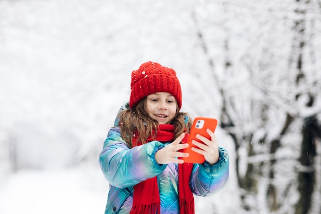 Cute little girl taking a selfie in the winter forest.