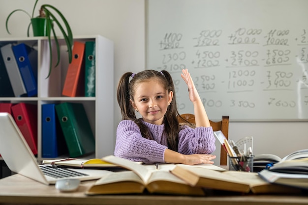 Cute little girl using laptop to study online at home