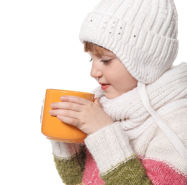 Cute little girl in warm clothes and with cup of hot cocoa drink on white