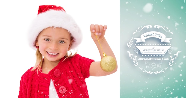 Cute little girl wearing santa hat holding bauble against green vignette