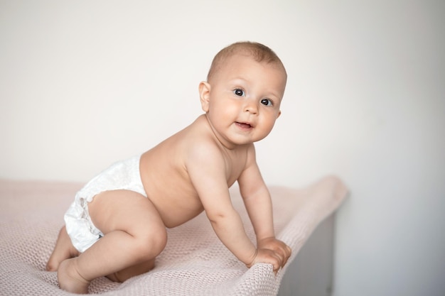 A cute little girl in a white diaper sits on a pink knitted blanket Lifestyle Happy Childhood Space for text