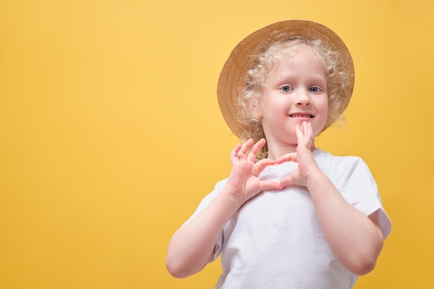 Cute little girl in a white tshirt having fun a child in a straw hat on a yellow background