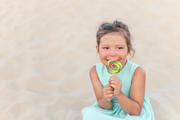 Cute little girl with big colorful lollipop. Child eating sweet candy bar. Sweets for young kids. Summer outdoor fun.