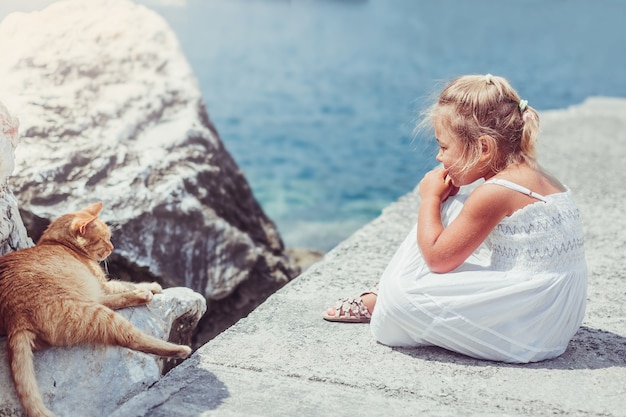 Cute little girl with cat  on the sea