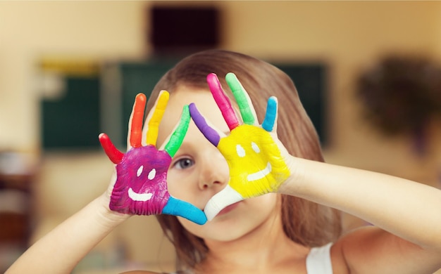 Cute little girl with colorful painted hands on  background