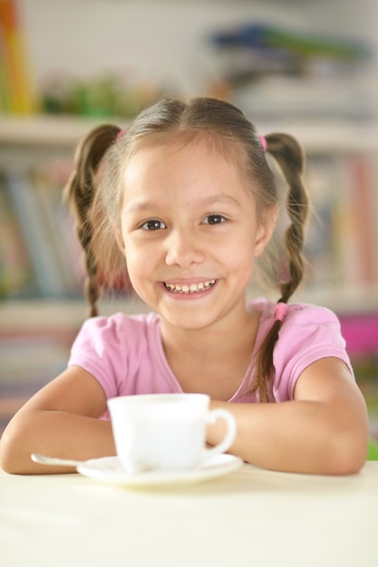 Cute little girl with cup  on the table