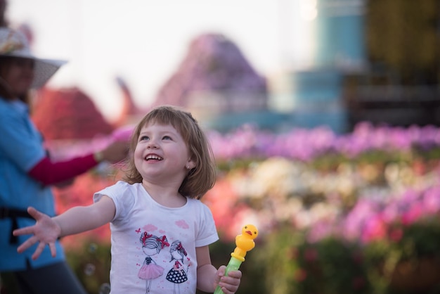 cute little girl with a doll in her hands in a beautiful flower garden