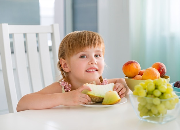 Cute little girl with fruits on the table