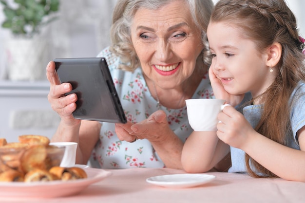 Cute little girl with her grandmother looking at tablet