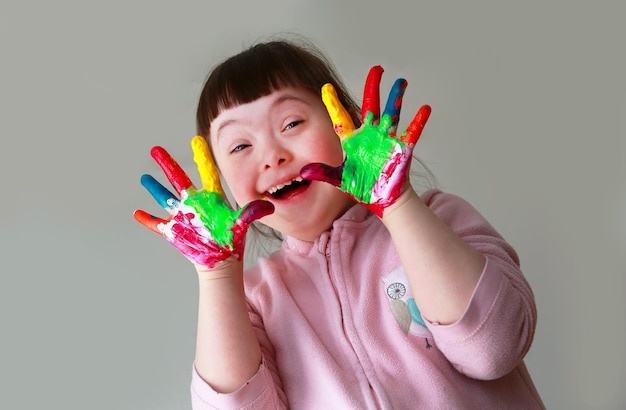 Cute little girl with painted hands. Isolated on grey background.