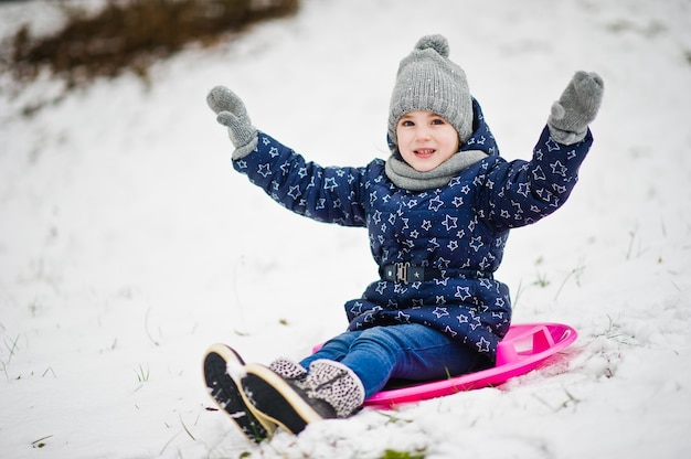 Cute little girl with saucer sleds outdoors on winter day.