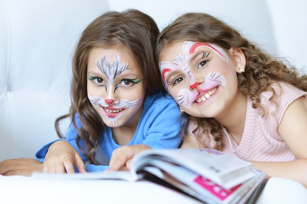 Photo cute little girls with face painted and magazine