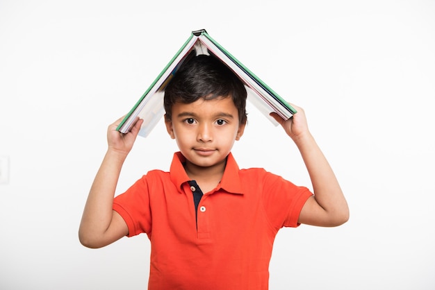 Cute little indian asian boy with hands stretched, holding book, magnifying glass or victory trophy, standing isolated over white background