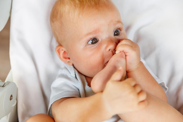 Cute little newborn girl with funny face sucking foot toe on white background Infant baby resting playing lying down on feeding chair at home Motherhood happy child concept