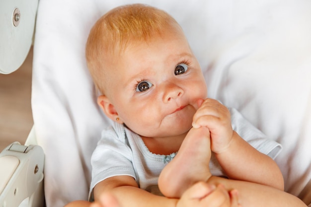 Cute little newborn girl with smiling face looking at camera on white background Infant baby resting playing lying down on feeding chair at home Motherhood happy child concept