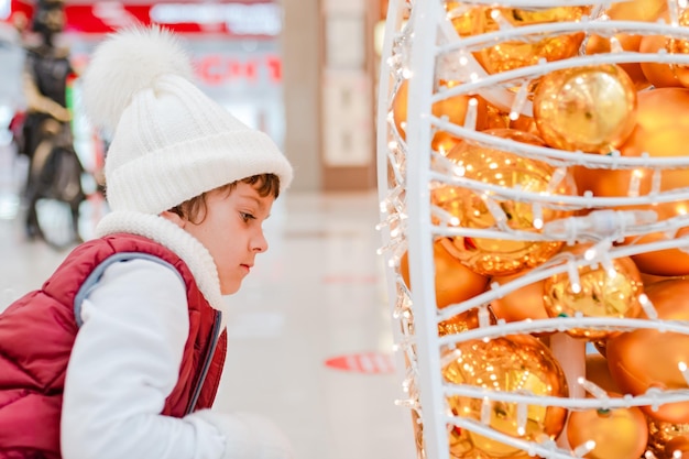 Cute little school kid boy on christmas market holidays christmas childhood and people concept