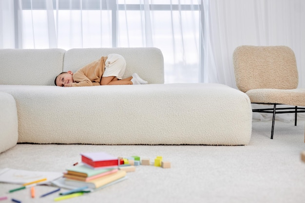 Cute little schoolboy have rest lying on sofa after drawing and having fun on floor adorable kid in ...