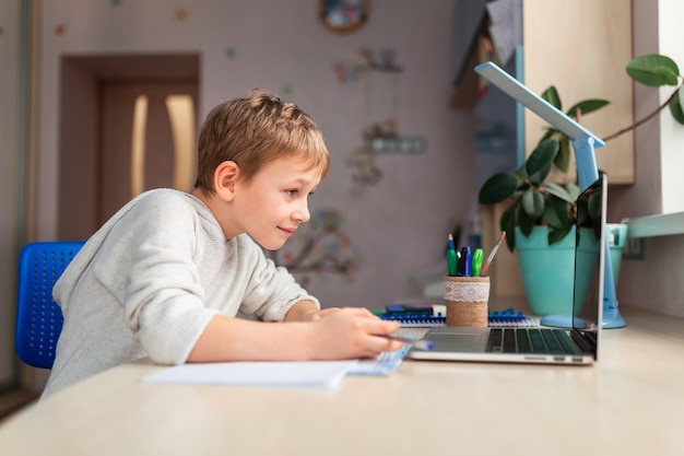 Cute little schoolboy studying at home doing school homework