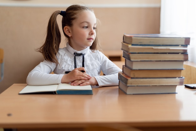 Cute little schoolgirl in her uniform in the classroom