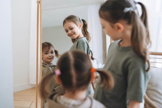 Cute little sisters girls looking on mirror at the home